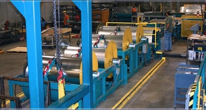A row of four, 10,000 pound sheet metal coils feeding the coil line.
